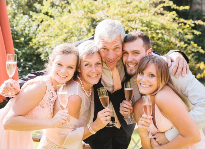 Familie hält Sektgläser in der Hand und schauen alle zusammen in die Kamera