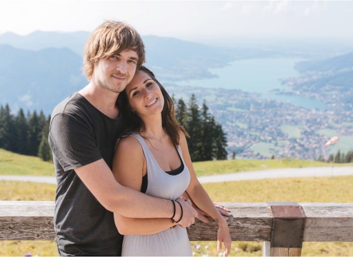 Paar schaut in die Kamera mit Tegernsee im Hintergrund