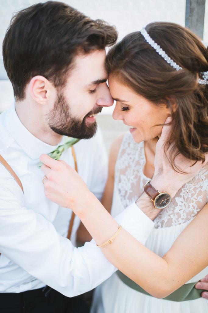 Brautpaar hält Köpfe beieinander und lacht