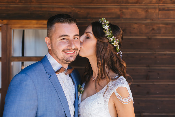 Braut küsst ihren Mann vor Holzfassade