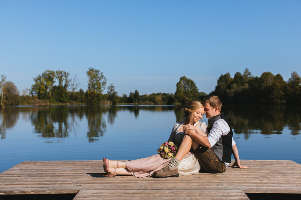 Brautpaar sitzt auf dem Steg vom Finsinger Weiher