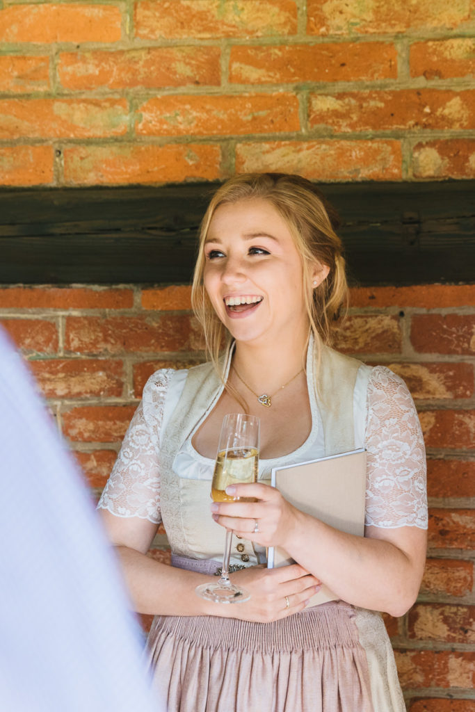 Braut lacht beim Sektempfang im Jagdhaus Eicherloh auf dem Balkon