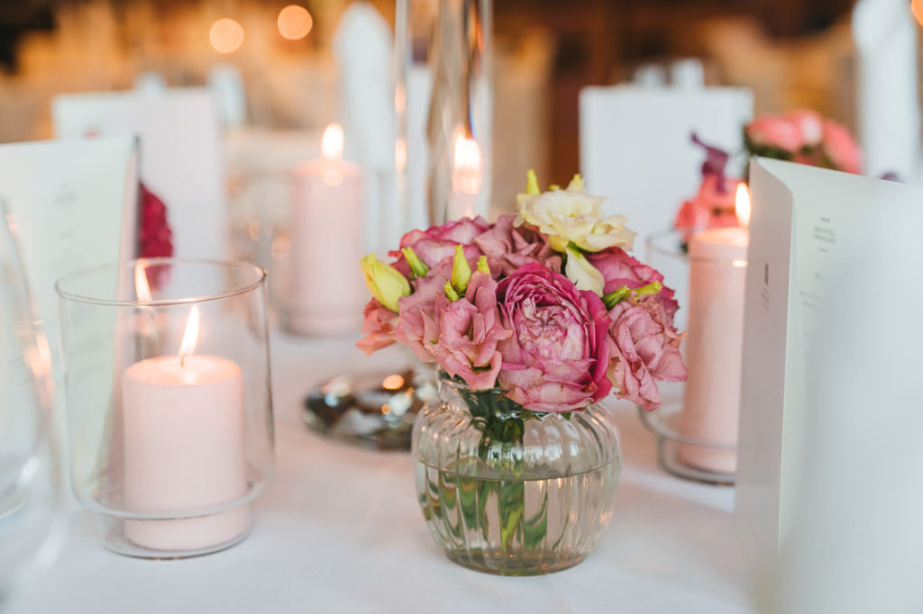 Blumen in Vase neben Kerze